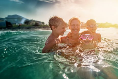 Kinder baden mit ihrer Mama im Meer