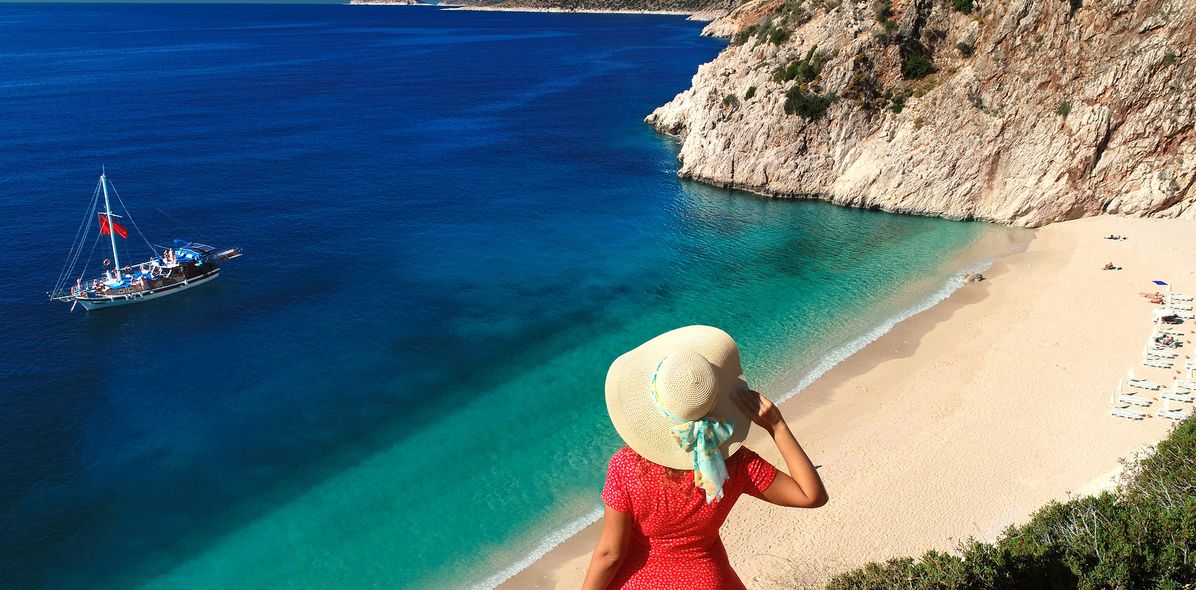 Frau mit Sonnenhut blickt auf eine Bucht an der türkischen Küste