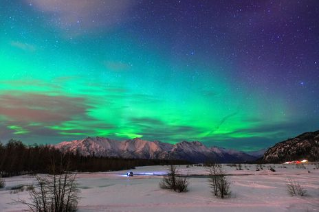 Polarlichter leuchten über den Knikriver bei verschneiter Landschaft