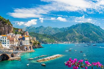 Panoramablick auf ein buntes Bergdorf am Meer mit Felsen, Bergen und Blumen an der Amalfiküste in Italien