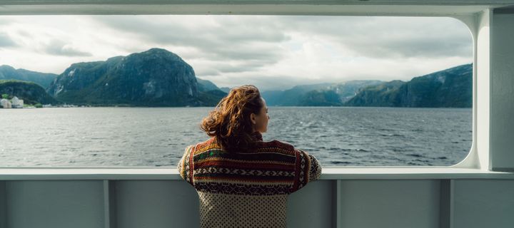 Frau blickt aus einem Kreuzfahrtschiff