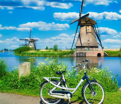 Fahrrad vor Windmühle in typischer niederländischer Landschaft