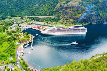 Kreuzfahrtschiff im Flam-Hafen am Sognefjord umgeben von grünen Bergen in Norwegen