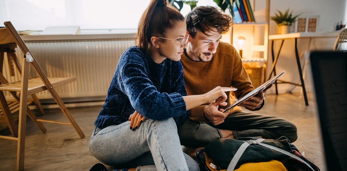 Pärchen am Tablet beim Koffer packen