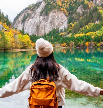 Frau schaut auf eine Herbstlandschaft im Jiuzhaigou-Nationalpark in Sichuan, China