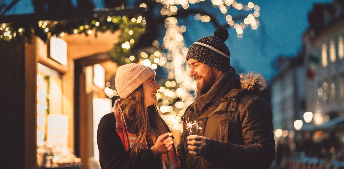 Paar mit Wunderkerzen am Weihnachtsmarkt