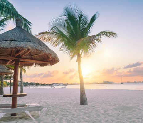 Strand bei Cancún mit Palmen und Sonnenuntergang über dem Meer