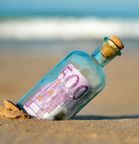 Flaschenpost mit Geld gefüllt am Strand