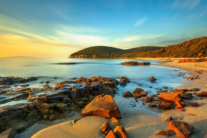 Cala Violina in der Toskana bei Sonnenuntergang mit Felsen und Meer
