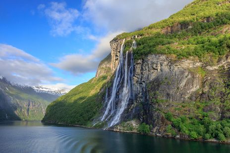 Wasserfall stürzt über grüne Felsen in das Geirangerfjord-Tal