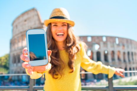 Frau mit Handy vor dem Kolosseum in Rom 