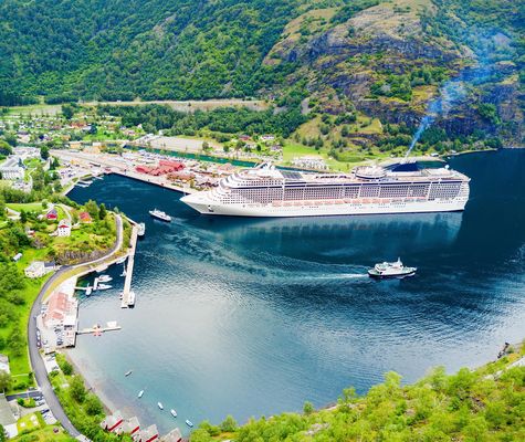 Kreuzfahrtschiff im Flam-Hafen am Sognefjord umgeben von grünen Bergen in Norwegen