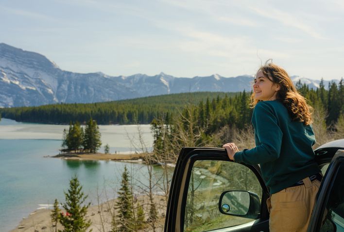Frau steigt aus ihrem Auto aus und blickt auf die Landschaft im Banff Nationalpark, Kanada