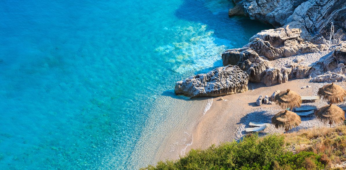  Der malerische Strand von Himare an der albanischen Riviera mit türkisfarbenem Wasser und Sonnenschirmen