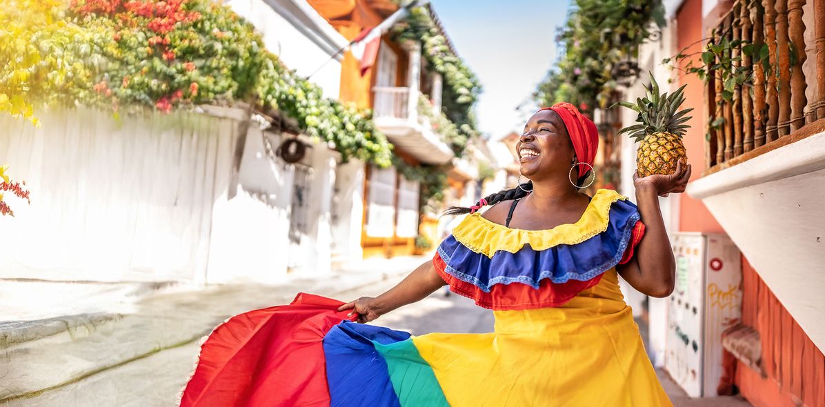 Eine fröhliche Frau in traditioneller kolumbianischer Tracht tanzt auf einer Straße in Cartagena
