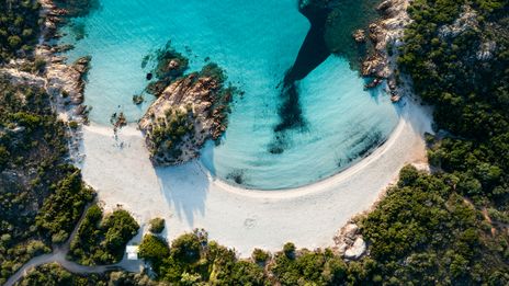 Luftaufnahme von einem Strand auf Sardinien mit weißem Sand und türkisfarbenem Wasser