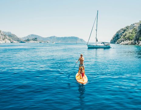 Paar auf einem Stand-up-Paddle in einer türkisblauen Bucht