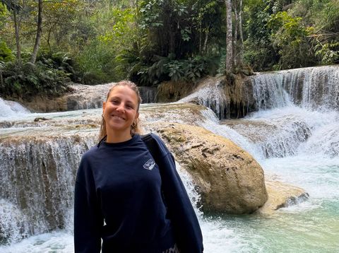Mitarbeiterin Julia unterwegs in Laos vor einem Wasserfall