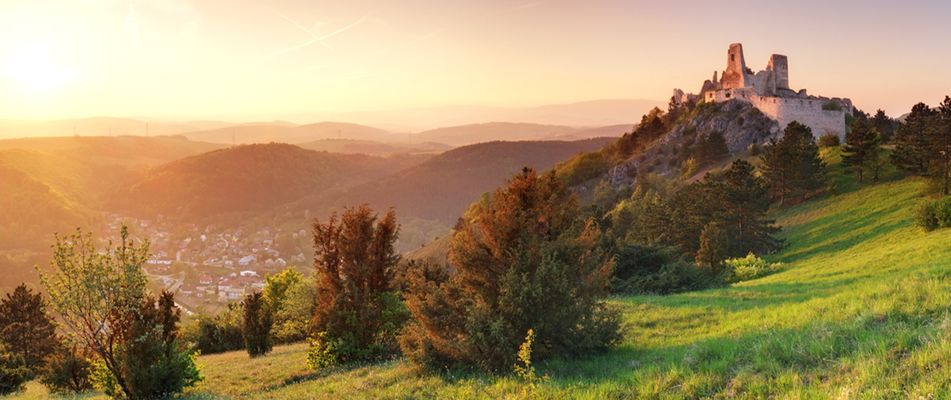 Burgruine in der Slowakei auf grünem Hügel bei Sonnenuntergang