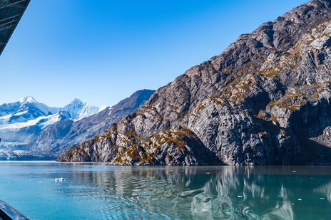 Blick vom Kreuzfahrtschiff auf die felsige Berglandschaft und schneebedeckten Gipfel der Glacier Bay in Alaska