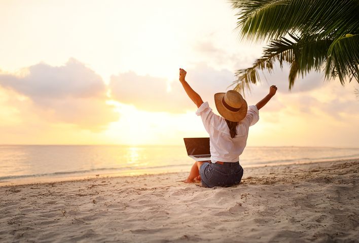 Frau am Strand mit einem Laptop auf den Beinen