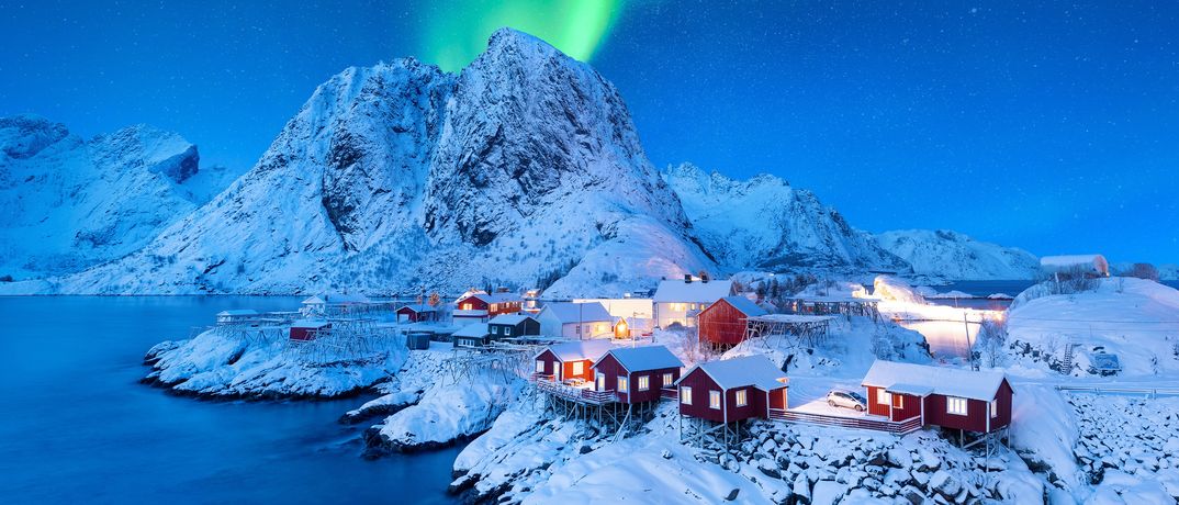Ein Fischerdorf in den Lotofen in einer Schneelandschaft mit Nordlichtern am Himmel