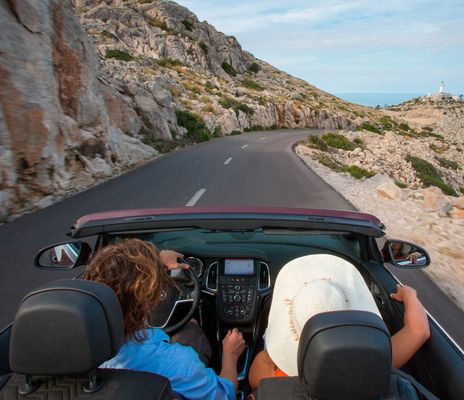 Personen fahren im Cabrio am Cap de Formentor eine Küstenstraße entlang, Blick aufs Meer