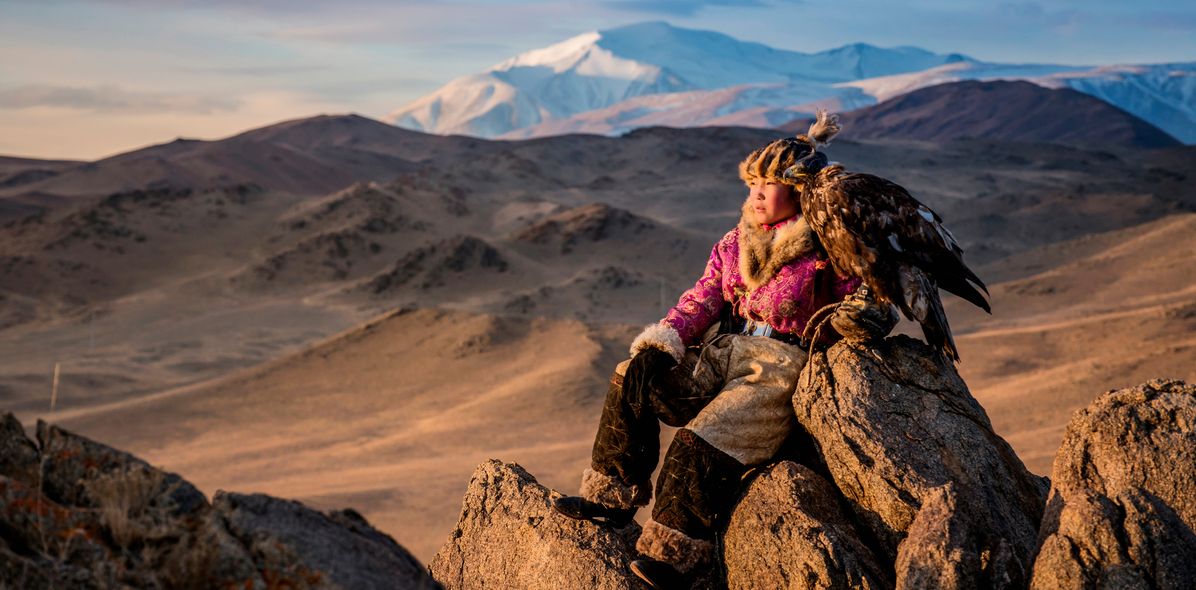 Eine Frau sitzt auf einem Felsen und schaut in die Ferne