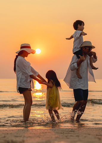 Familie in den Sommerferien bei Sonnenuntergang am Strand