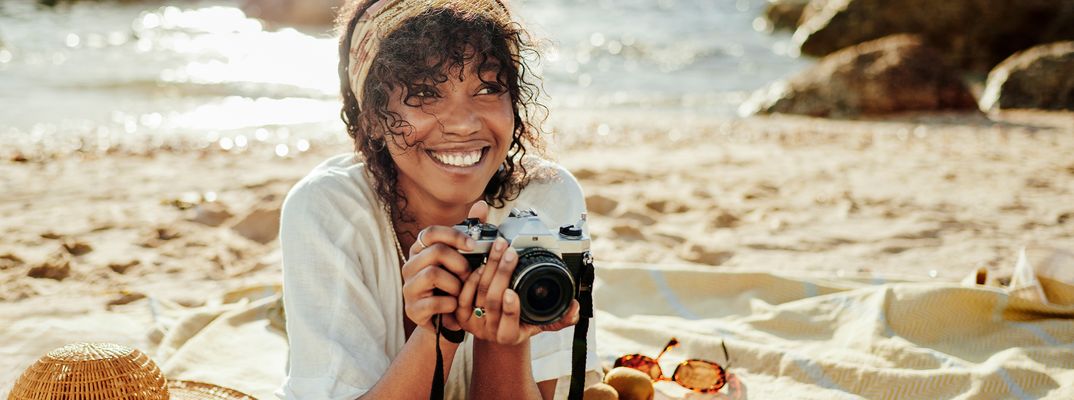 Lachende Frau am Strand mit Kamera