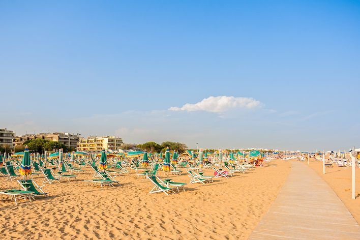 Sandstrand in Bibione mit Liegestühlen und blauem Himmel