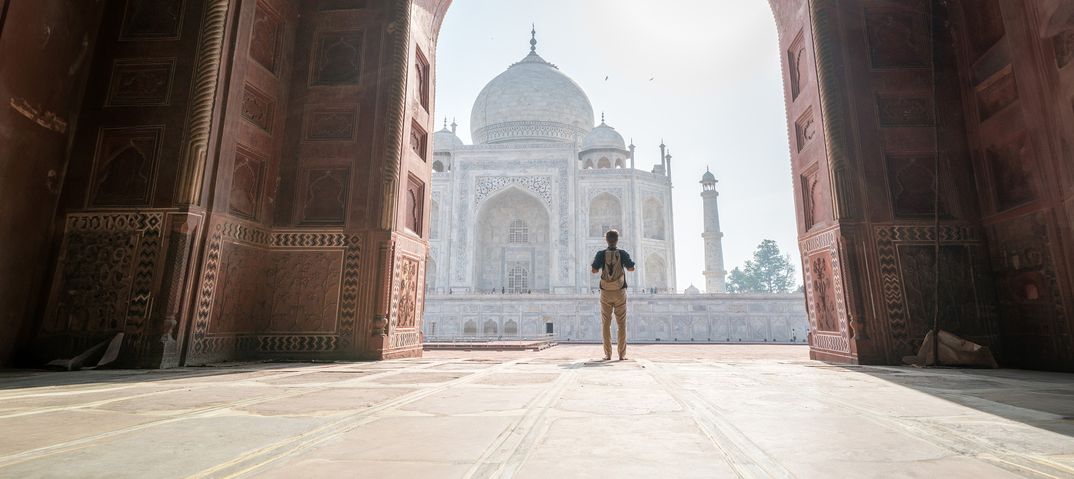 Mann steht im Torbogen mit Blick auf den Taj Mahal