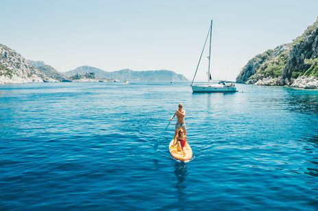 Paar auf einem Stand-up-Paddle in einer türkisblauen Bucht