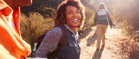 Frau und Mann lachen während einer Wanderpause und blicken in die Sonne