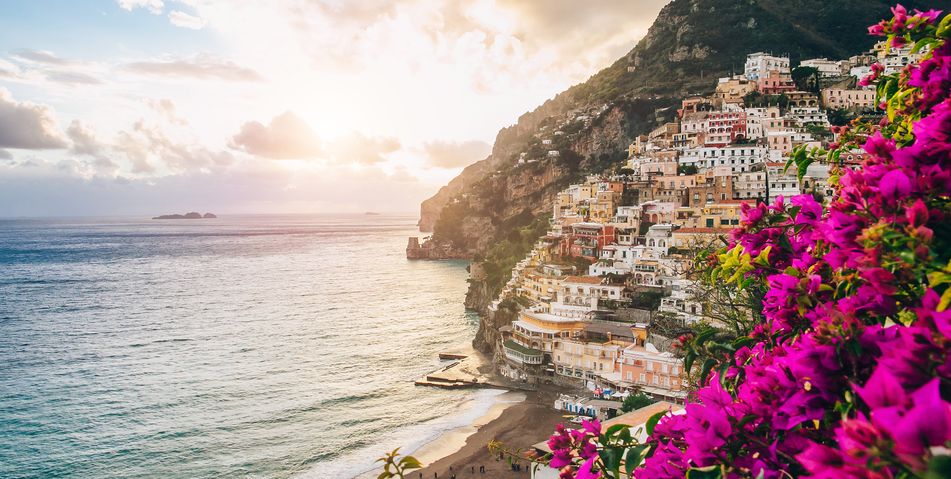 Panoramablick von der Küste Positanos in Italien über pinke Blumen auf Meer und Küstendörfer