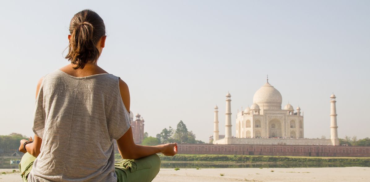 Frau sitzt im Schneidersitz vor dem Taj Mahal