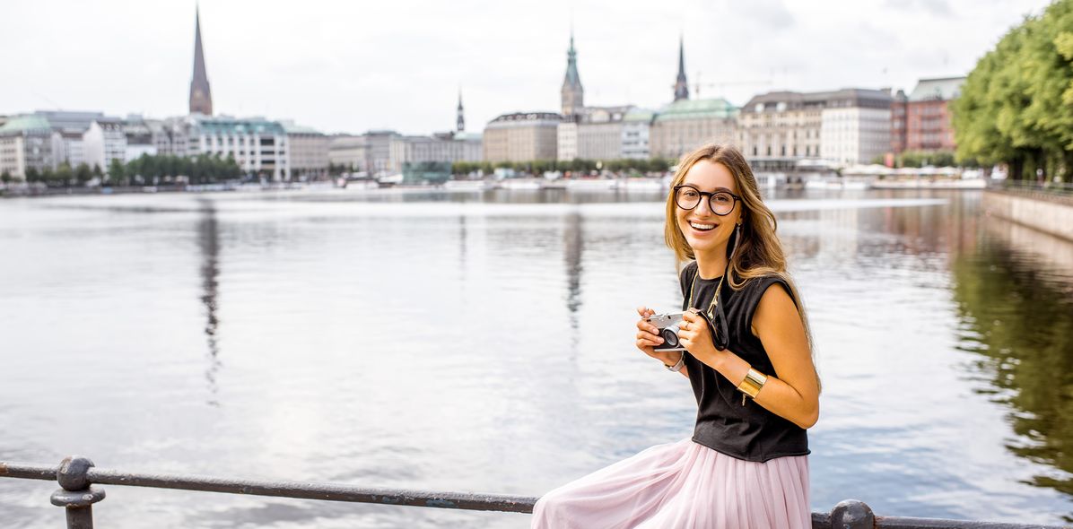 Frau sitzt am Alsterufer mit Blick auf Hamburg