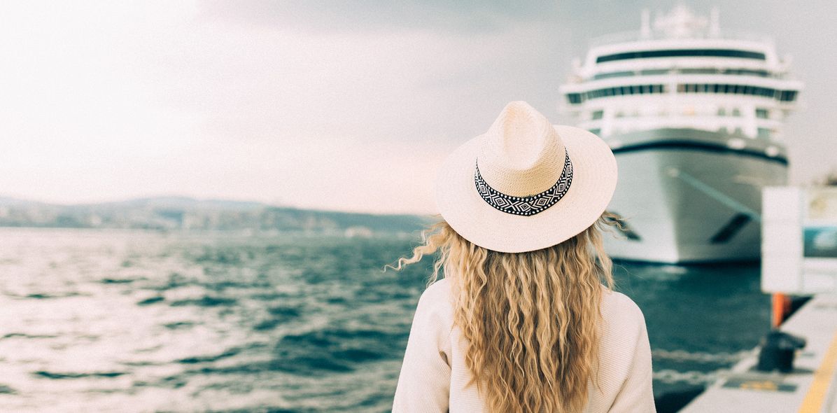Frau steht vor einem Kreuzfahrtschiff