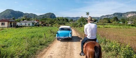 Pferd und Oldtimer in der grünen Landschaft von Viñales