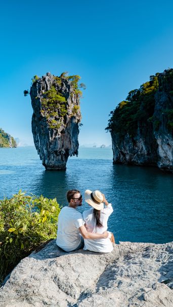 Ein Paar sitzt auf einem Felsen und betrachtet den James Bond Felsen in Phuket