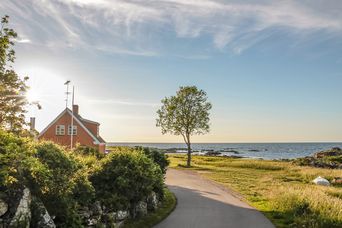 Weite Landschaft und Küste auf der Insel Bornholm mit Blick auf rotes skandinavisches Haus
