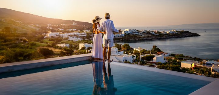 Paar steht am Infinity-Pool und schaut über die Landschaft bei goldenem Licht