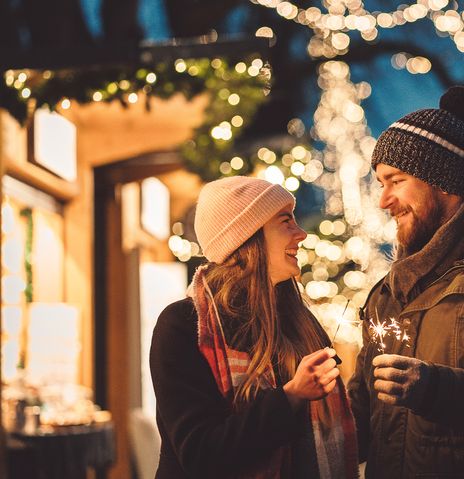 Paar mit Wunderkerzen auf Weihnachtsmarkt