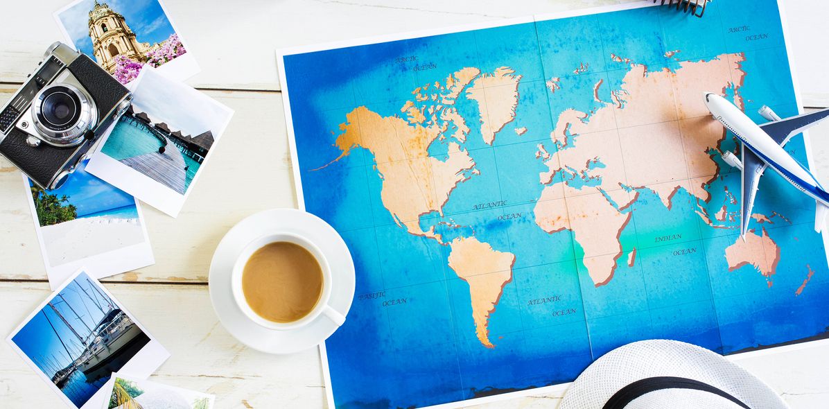 Auf Tisch liegt Weltkarte mit Bildern, Kaffeetasche und Kamera