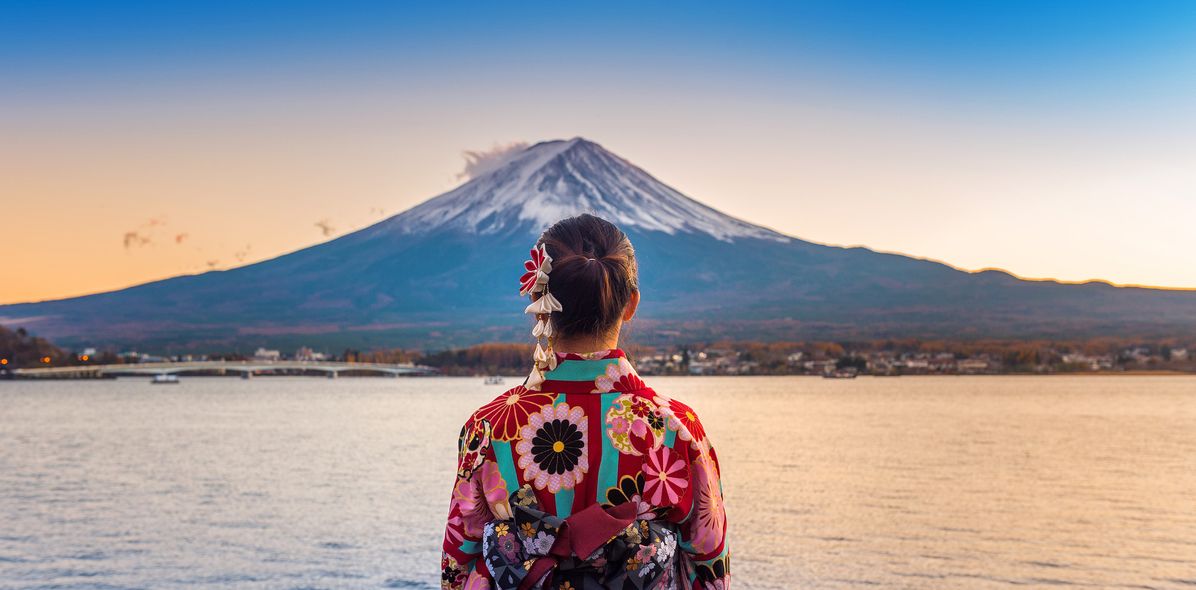 Japanische Frau steht mit dem Rücken zur Kamera am See und schaut auf den Fuji in Japan