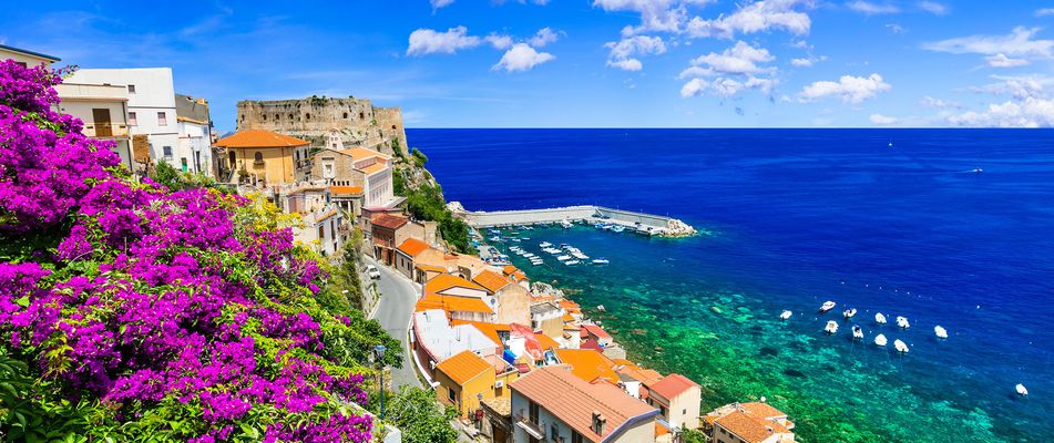 Bunte Altstadthäuser von Scilla mit blühenden Bougainvilleen über dem Meer