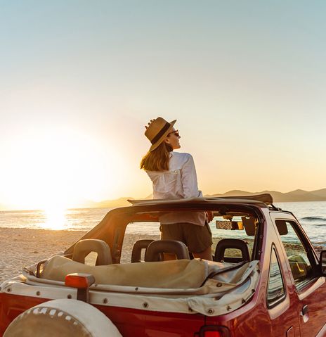 Frau blickt im Auto aufs Meer