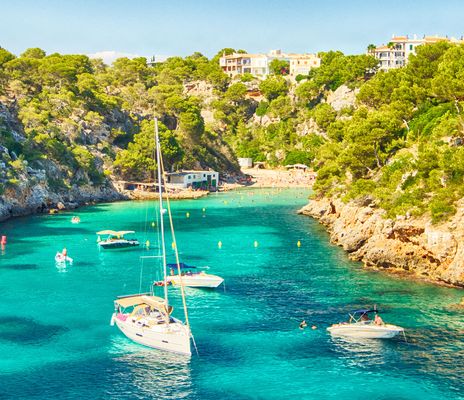 Felsige Bucht auf Mallorca mit Segelbooten und glasklarem Meer im Sommer