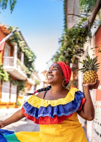 Eine fröhliche Frau in traditioneller kolumbianischer Tracht tanzt auf einer Straße in Cartagena