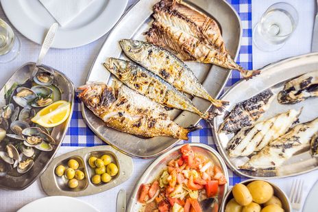 Blick von oben auf das typisch portugiesische Gericht aus angerichteten gegrillten Fisch mit Meeresfrüchten und Beilagen